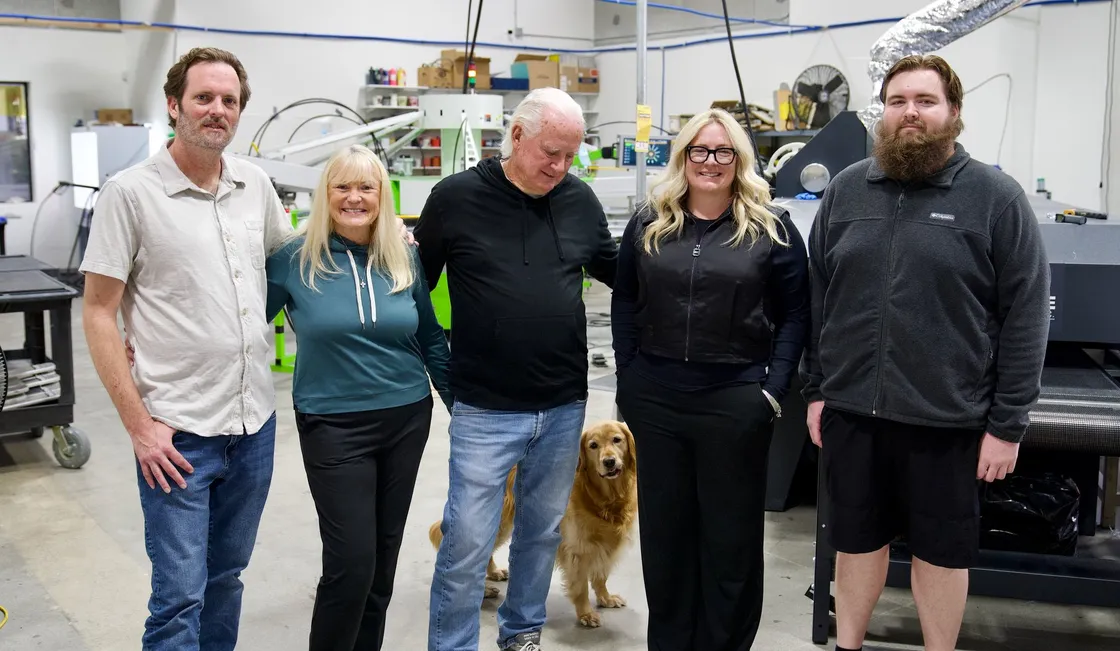 The Lamb family and the shop dog standing together on the production floor