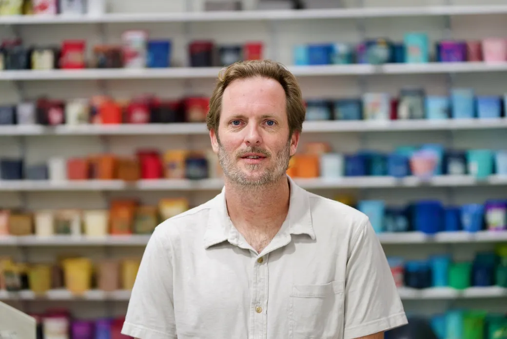 Ryan Lamb standing in the shop in front of the shelves where the ink is kept